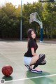 A woman kneeling on a basketball court with a basketball.