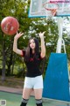 A woman in a black shirt and white shorts playing basketball.