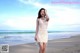 A woman in a white dress standing on a beach.