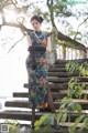 A woman in a blue and orange dress standing on some steps.