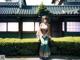 A woman in a kimono sitting on a bench in front of a building.