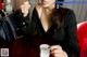 A woman sitting at a table with a cup of coffee.