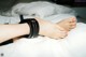 A woman's feet on a bed with a black and red bracelet.