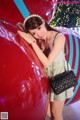 A woman leaning against a large red balloon.