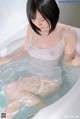 A woman sitting in a bathtub with her legs in the water.