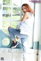 A woman sitting on a window sill in front of a window.