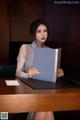 A woman sitting at a desk holding a folder.