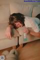 A woman laying on a couch holding a bottle of water.