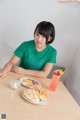 A woman sitting at a table with a plate of food and a drink.