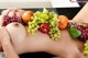 A woman laying on top of a table covered in fruit.