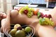 A naked woman laying on a counter with a basket of fruit.