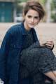 A woman sitting on the ground wearing a denim jacket.