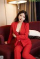 A woman in a red suit sitting on a red couch.