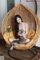 A woman sitting in a hanging chair holding a cat.