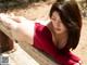 A woman in a red dress laying on a wooden bench.