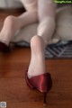 A close up of a woman's legs wearing red shoes.