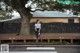 A woman standing on a bench in front of a tree.