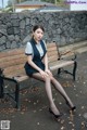 A woman sitting on a bench with her legs crossed.