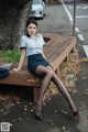 A woman sitting on a bench in a skirt and shirt.