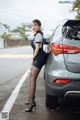 A woman standing next to a car on the side of the road.