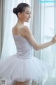 A woman in a white tank top and a white tutu.