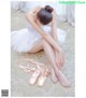 A young ballerina sitting on the floor with her ballet shoes.