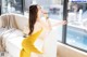 A woman in a yellow dress sitting on a white couch.