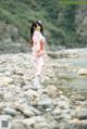 A woman in a kimono standing on a rocky beach.