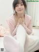 A woman sitting on top of a bed wearing white tights.