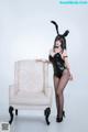 A woman in a bunny costume posing next to a chair.