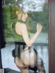 A woman in lingerie holding a wand in front of a window.