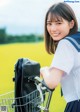 A woman in a school uniform standing next to a bicycle.