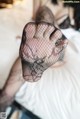 A woman in fishnet stockings sitting on a bed.