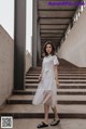 A woman in a white dress is standing on some steps.