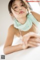 A young woman wearing a green scarf laying on a bed.