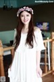 A woman wearing a white dress and a flower crown.