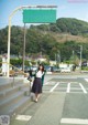 A woman standing in front of a green street sign.