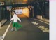 A woman in a white shirt and green skirt standing in a parking lot.