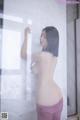 A naked woman standing in front of a glass door.