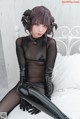 A woman in a black bodysuit sitting on a bed.