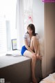 A woman sitting on top of a bed next to a window.