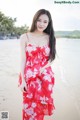 A woman in a red dress standing on a beach.