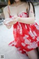 A woman in a red dress holding a handful of sand.