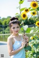 A woman standing next to a bunch of sunflowers.