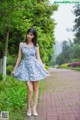 A woman in a blue dress standing on a brick walkway.