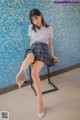 A woman in a school uniform sitting on a chair.