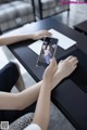 A woman sitting at a table with a cell phone in her hand.