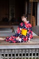 A woman in a kimono sitting on a wooden bench.