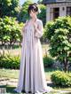 A woman in a long white dress standing in a garden.