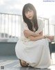 A woman in a white dress sitting on a ledge.